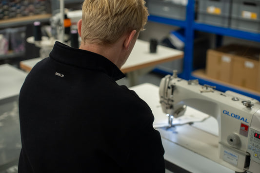 Naaister werkt met de hand aan een MIKLN-shirt in het atelier in Groningen
