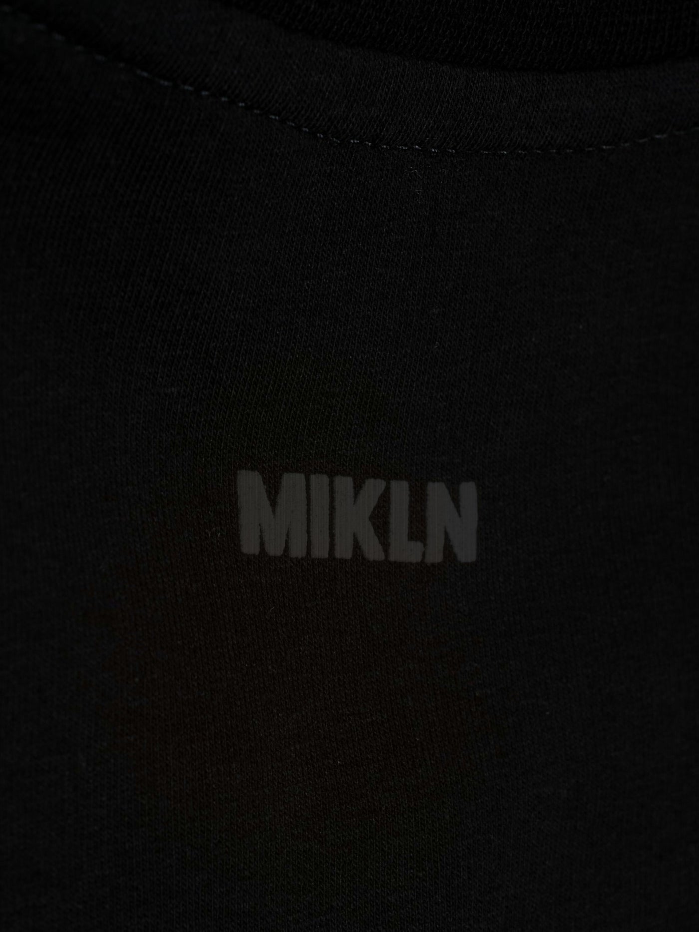 MIKLN T 02 zwart close-up van het ton-sur-ton logo op de stof