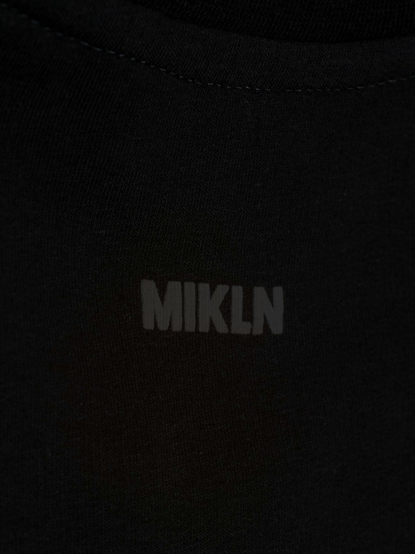 MIKLN T 02 zwart close-up van het ton-sur-ton logo op de stof