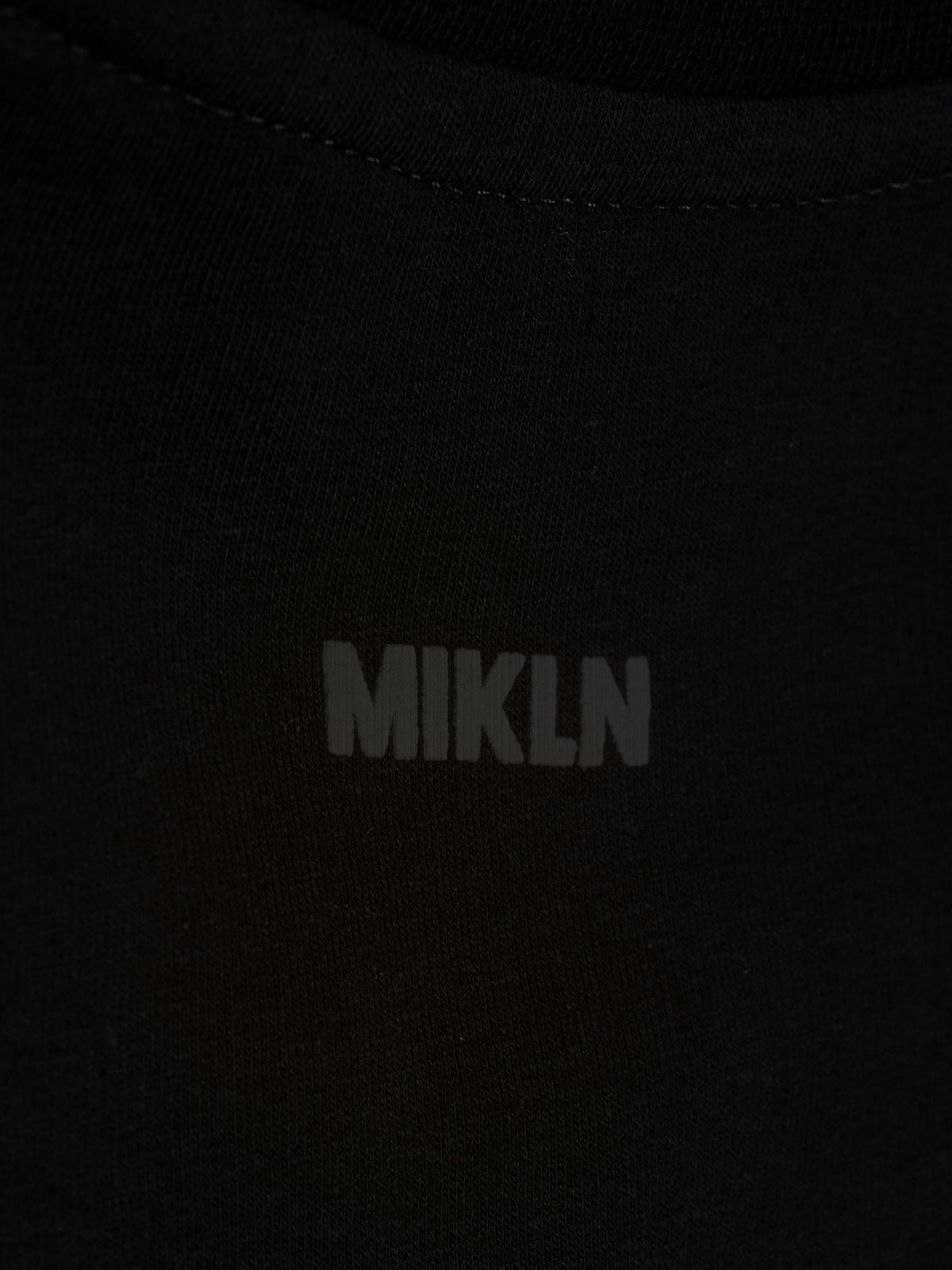 MIKLN T 03 zwarte long sleeve close-up van het ton-sur-ton logo op de borst