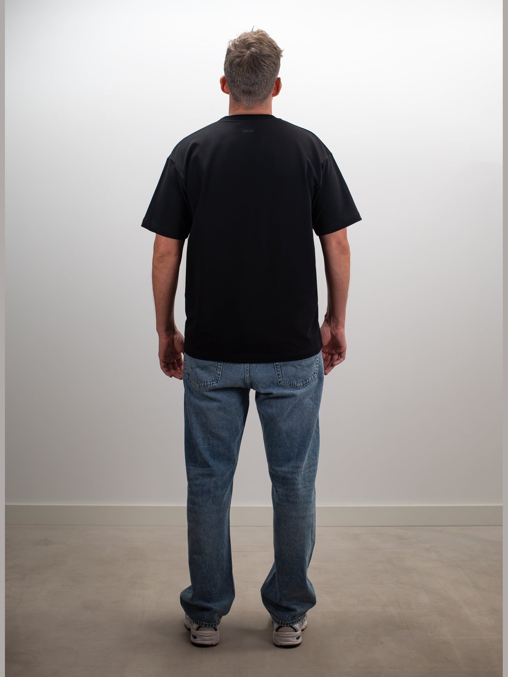 Man draagt het MIKLN Original T-shirt in zwart, achterkant
