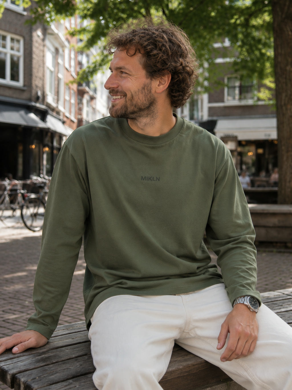 MIKLN T 03 groene long sleeve gedragen op een bankje in de stad, relaxed fit