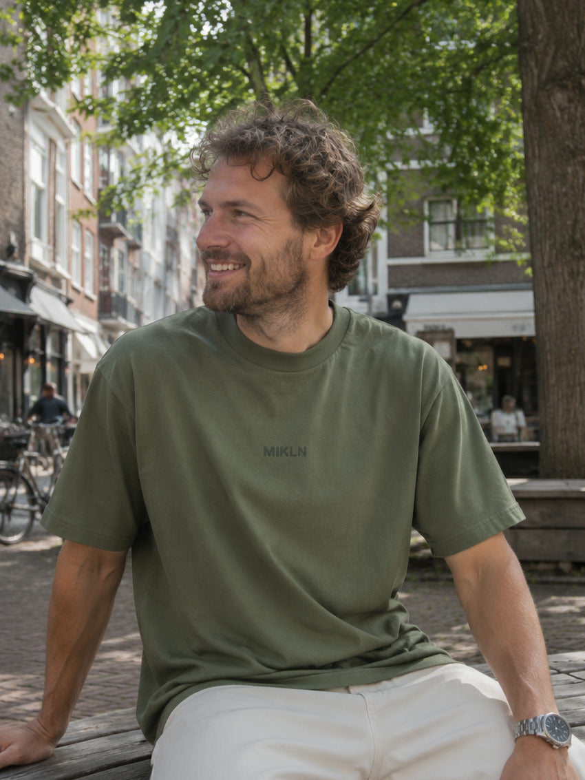 mikln t 02 groen t-shirt gedragen op een bankje in amsterdam, ton-sur-ton logo