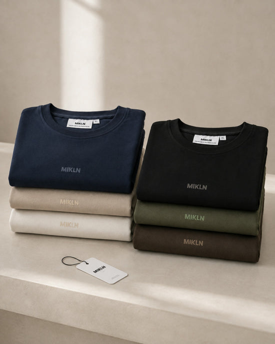 Zes gevouwen MIKLN Original T-shirts in navy, beige, off-white, zwart, groen en bruin, handgemaakt in Nederland