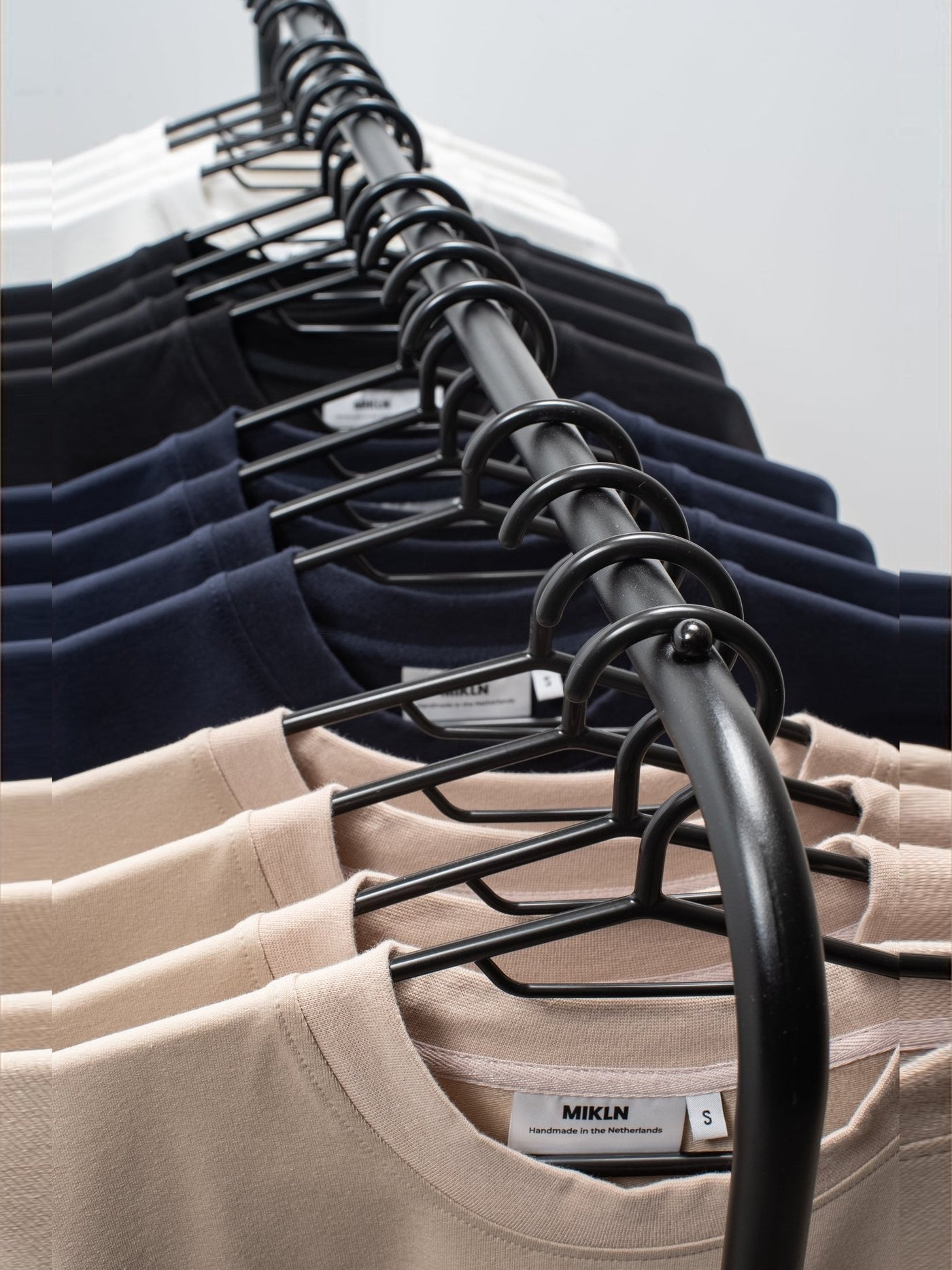 Kledingrek met MIKLN T-shirts in het atelier, handgemaakt in Nederland
