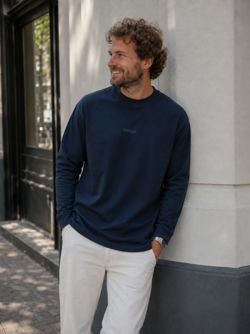MIKLN T 03 navy long sleeve gedragen tegen een gevel in de stad, relaxed fit