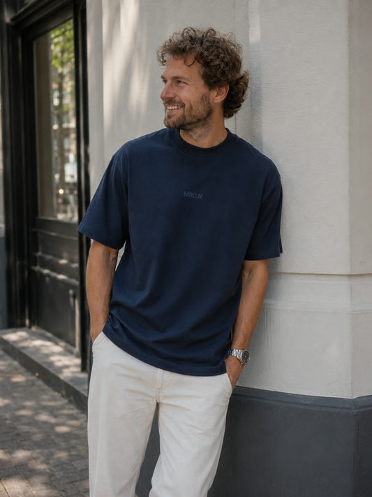 MIKLN T 02 navy T-shirt gedragen tegen een gevel in Amsterdam, relaxed fit