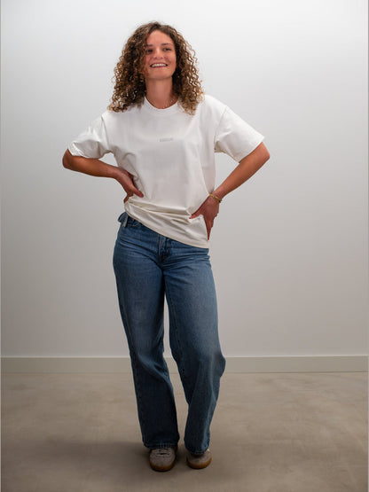 Vrouw draagt het MIKLN Original T-shirt in off-white met relaxed fit