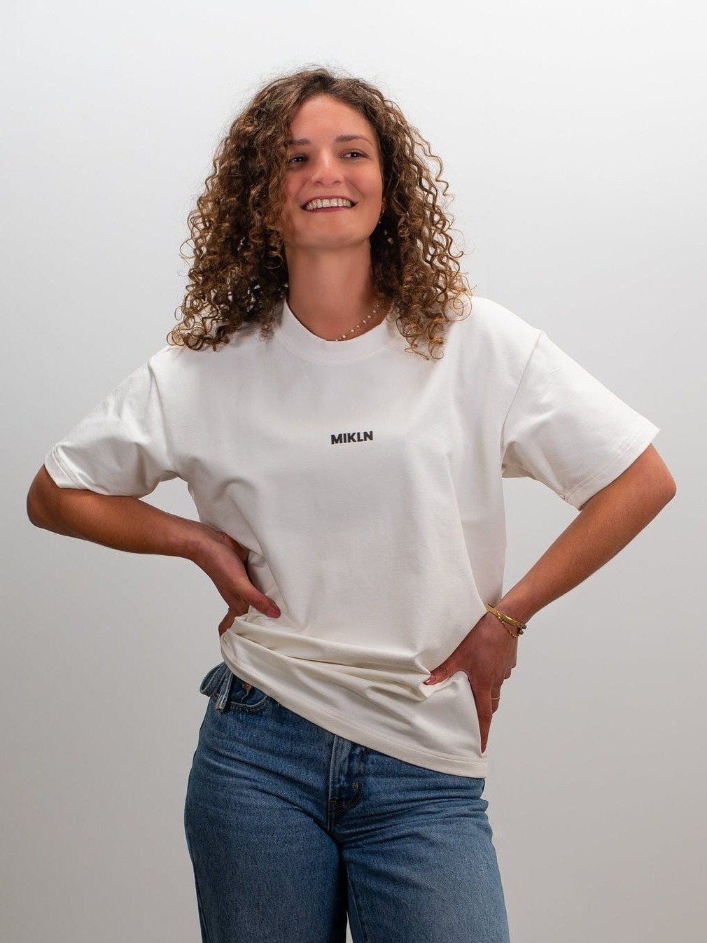 Vrouw draagt het MIKLN Original T-shirt in off-white met relaxed fit